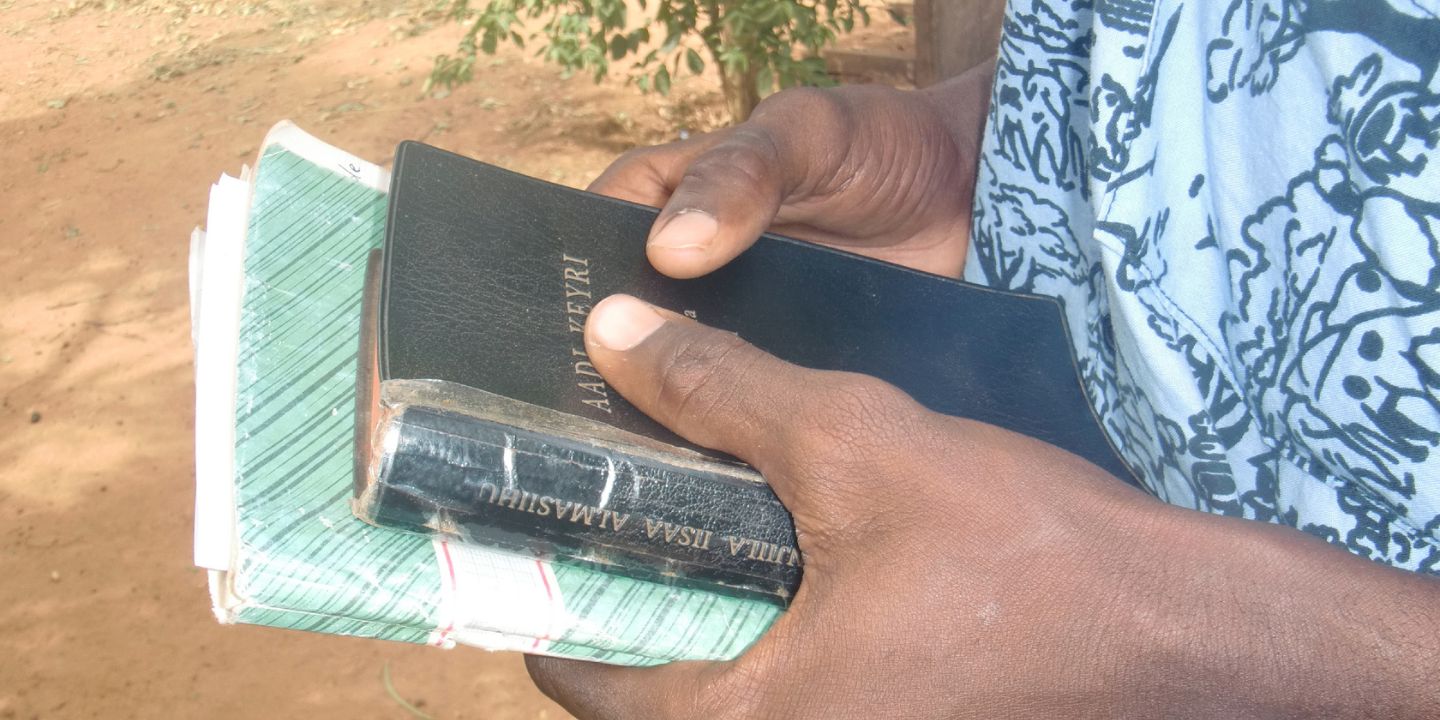 En person holder en bibel mellom hendene