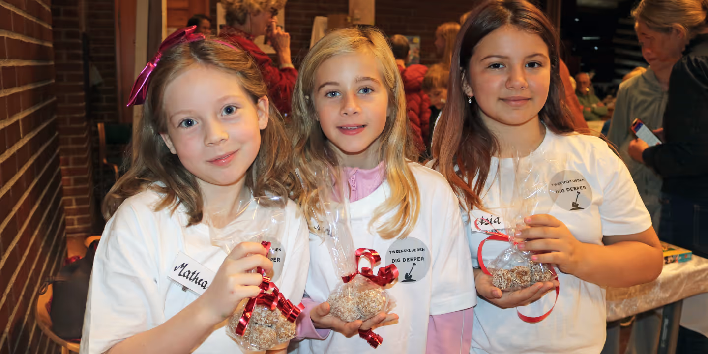 Tre jenter holder fram egenlagde salgsprodukter