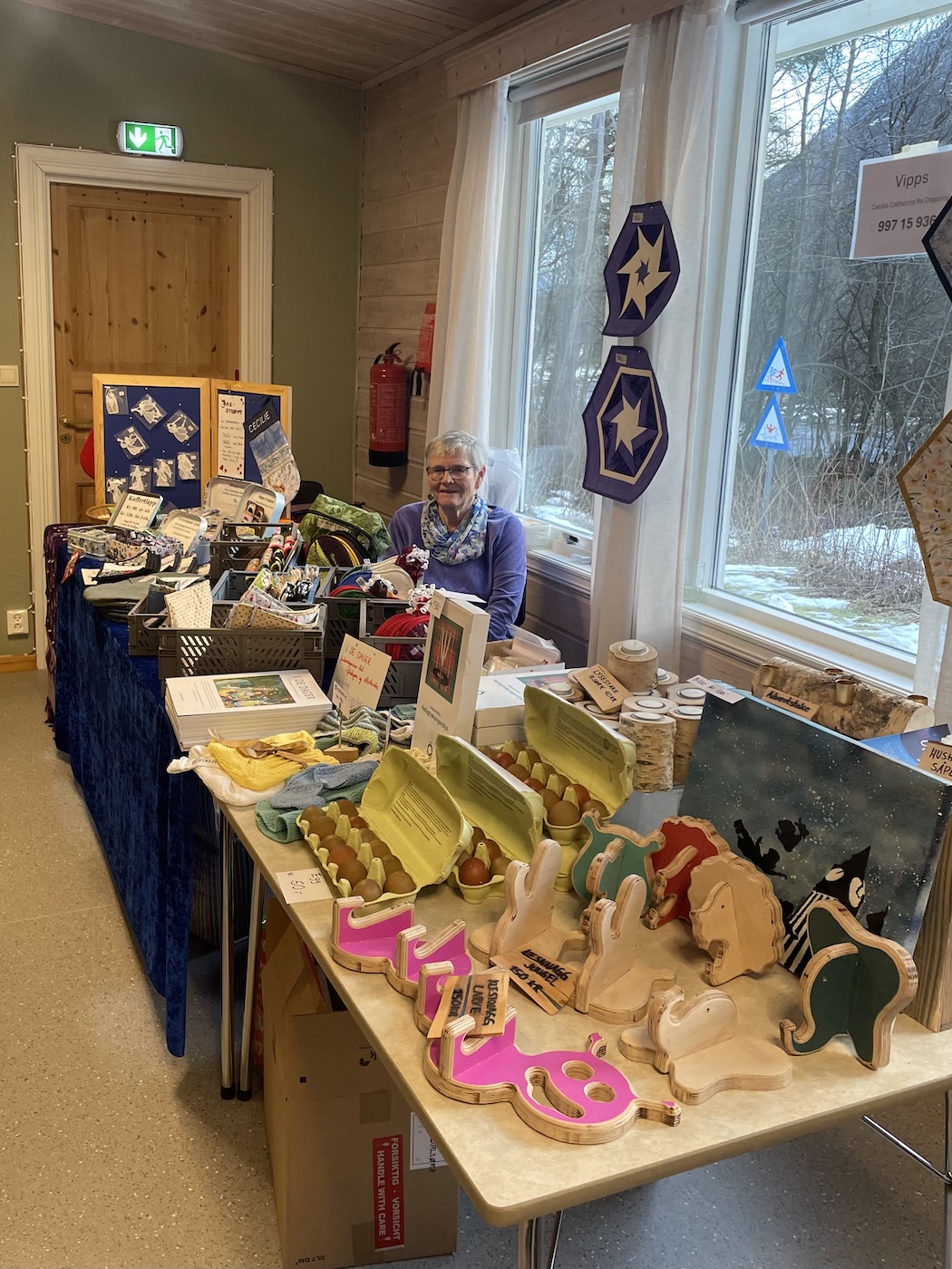 Person som sitter bak salgsbord på julemesse