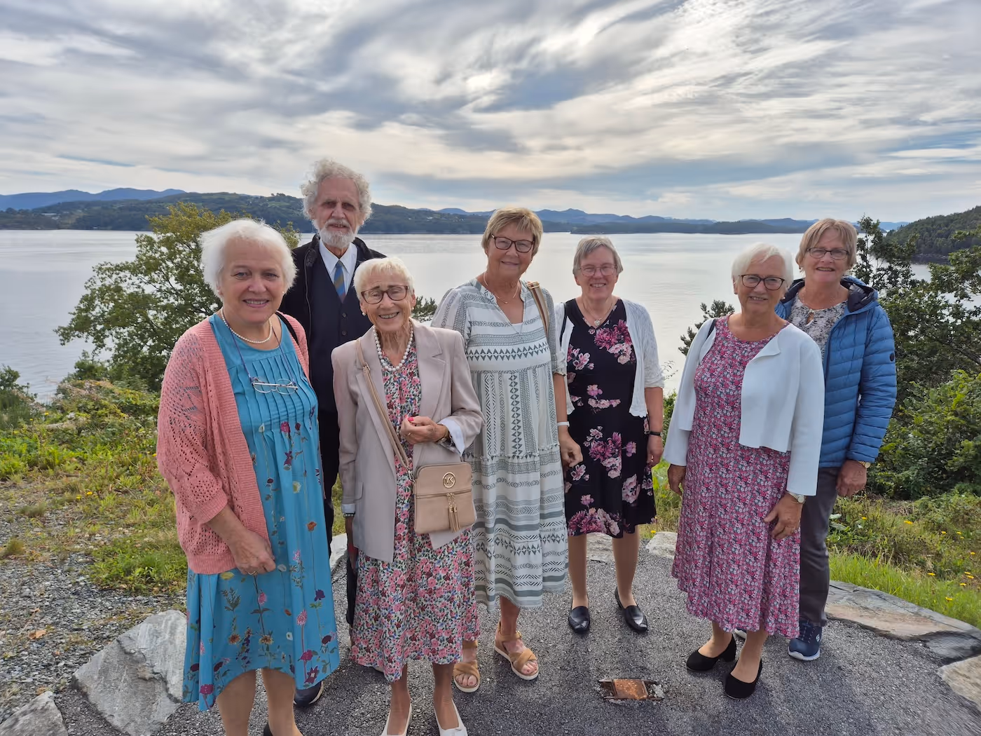 Sju personer avbildet foran en fjord