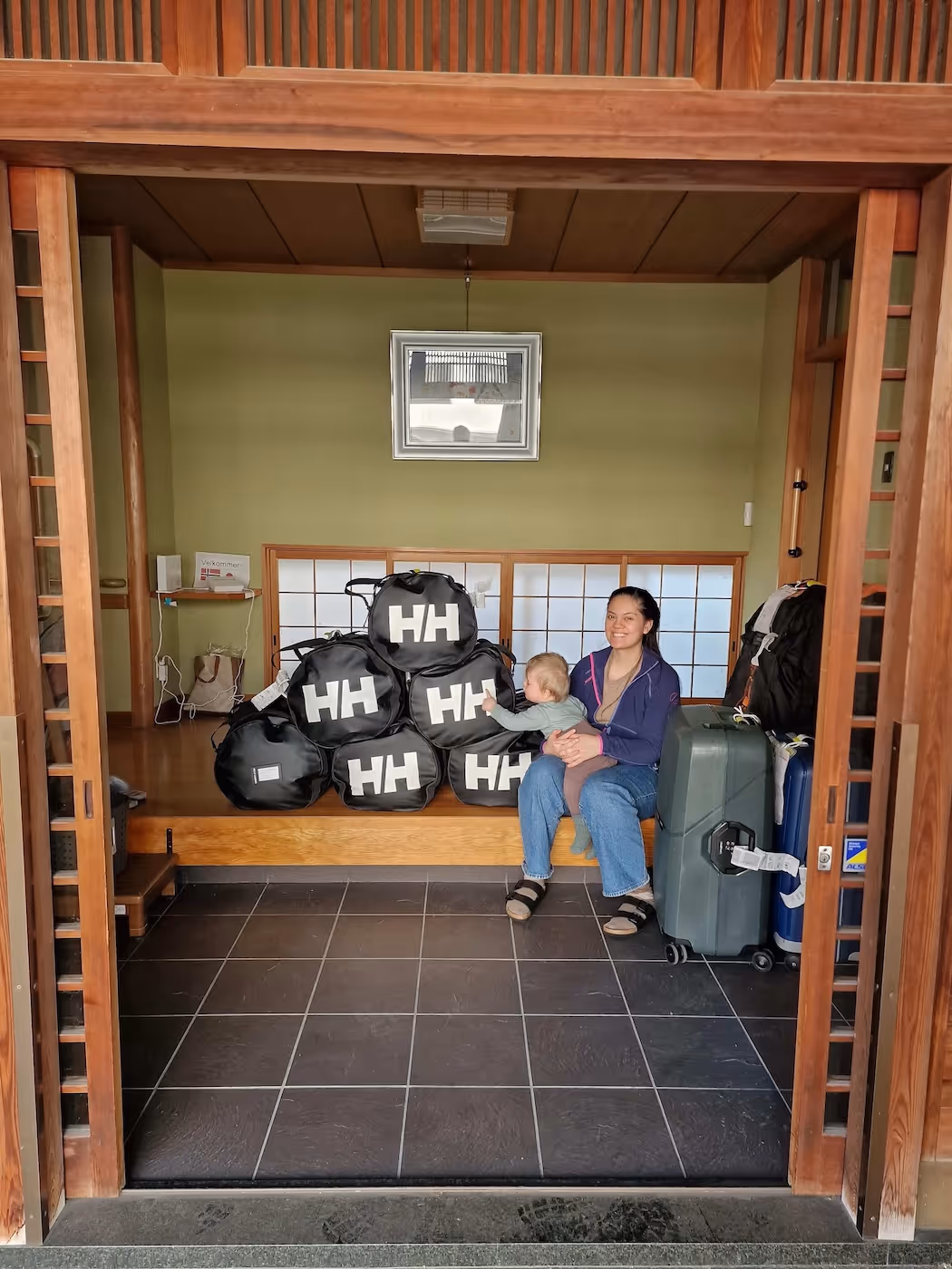 Bildet viser en kvinne og en baby sittende blant mye bagasje