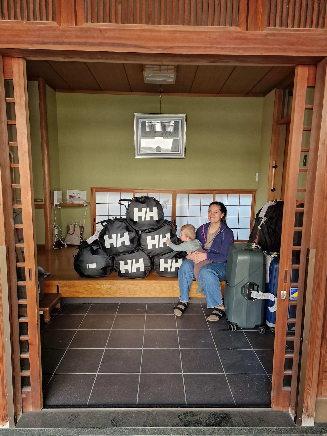 Bildet viser en kvinne og en baby sittende blant mye bagasje