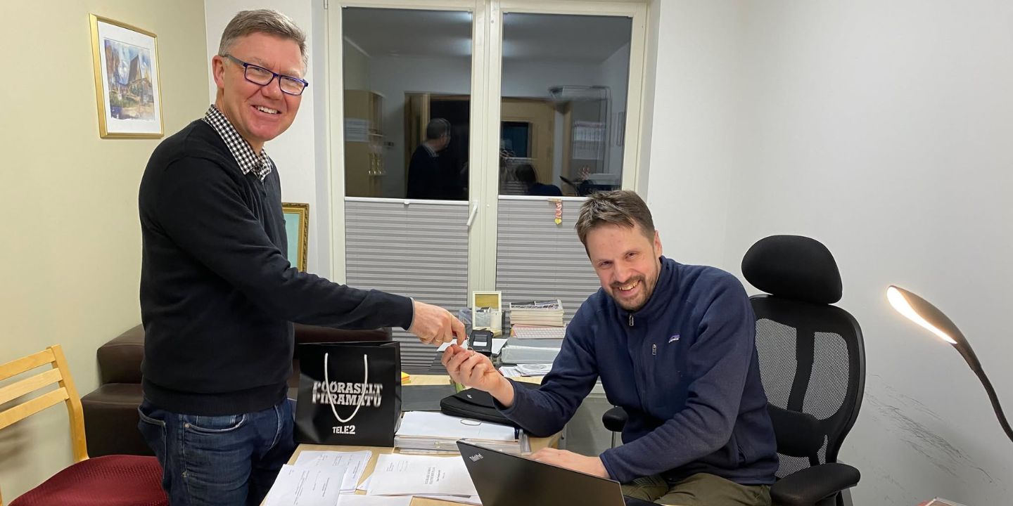 Bildet viser to personer, hvorav den ene overrekker et sett med nøkler til den andre