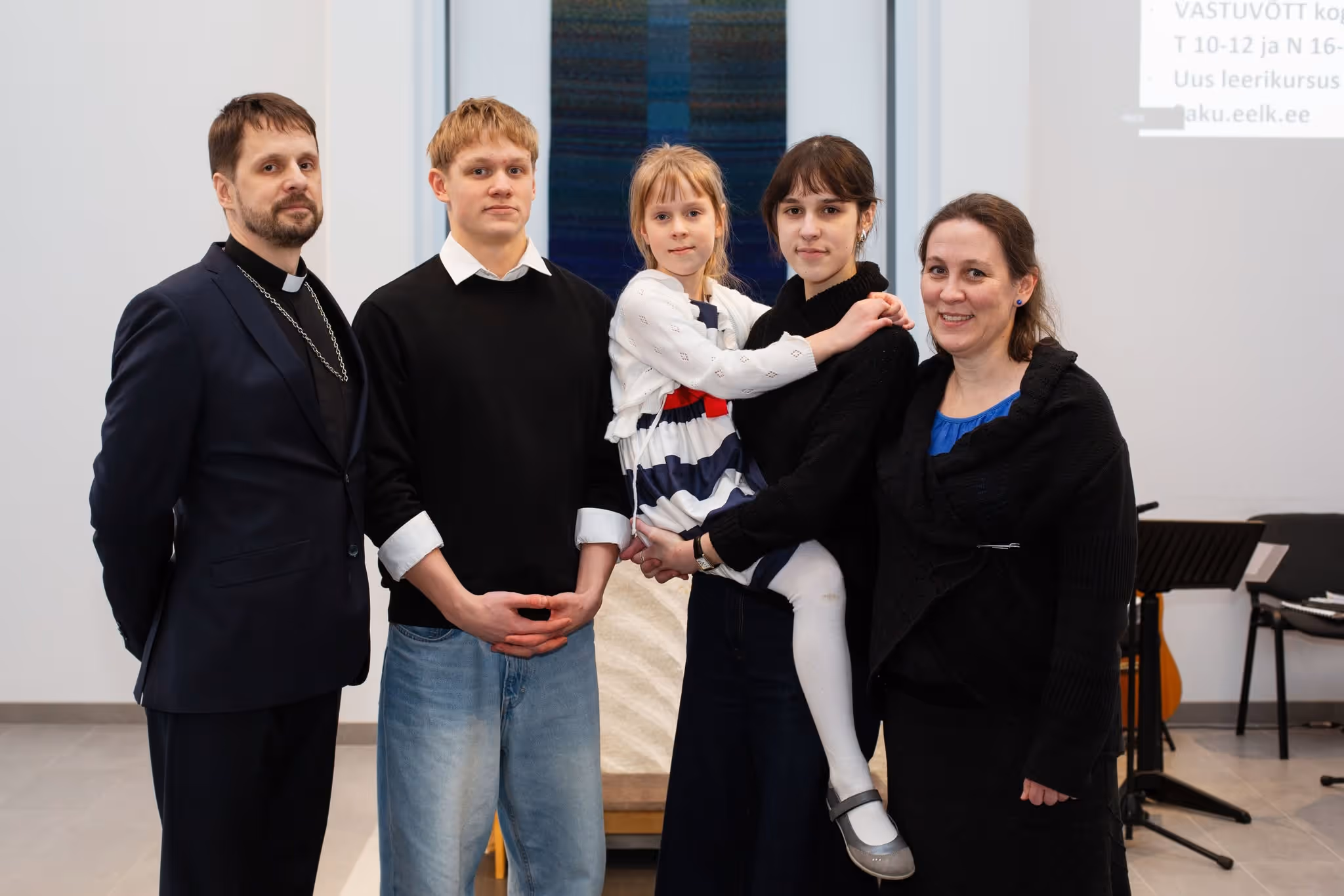 Bildet viser en familie som står oppstilt i et kirkerom