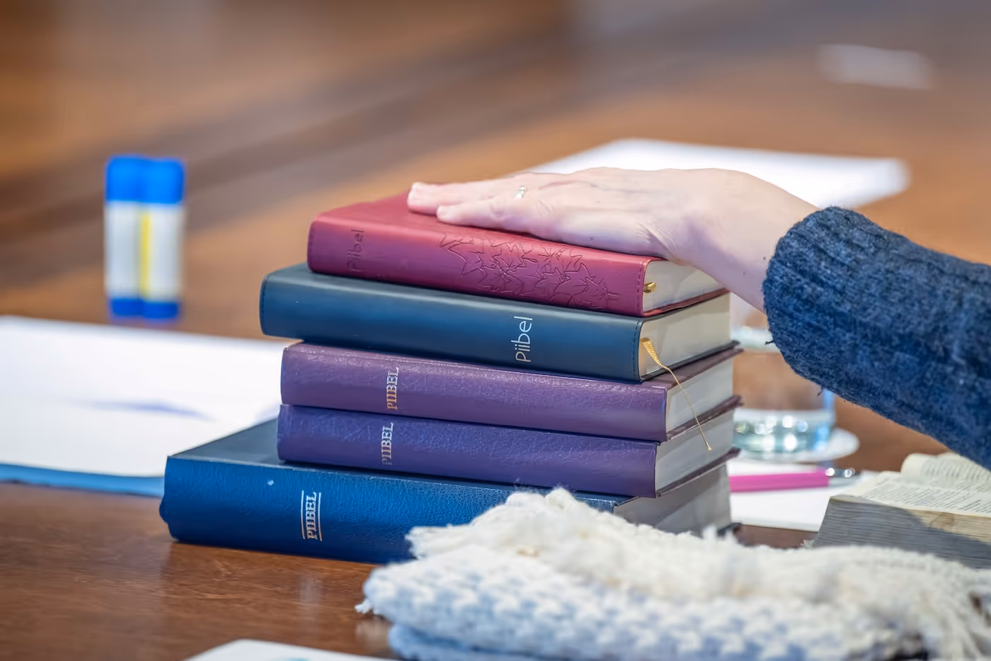 Bildet viser en hånd som hviler på en stabel med bibler