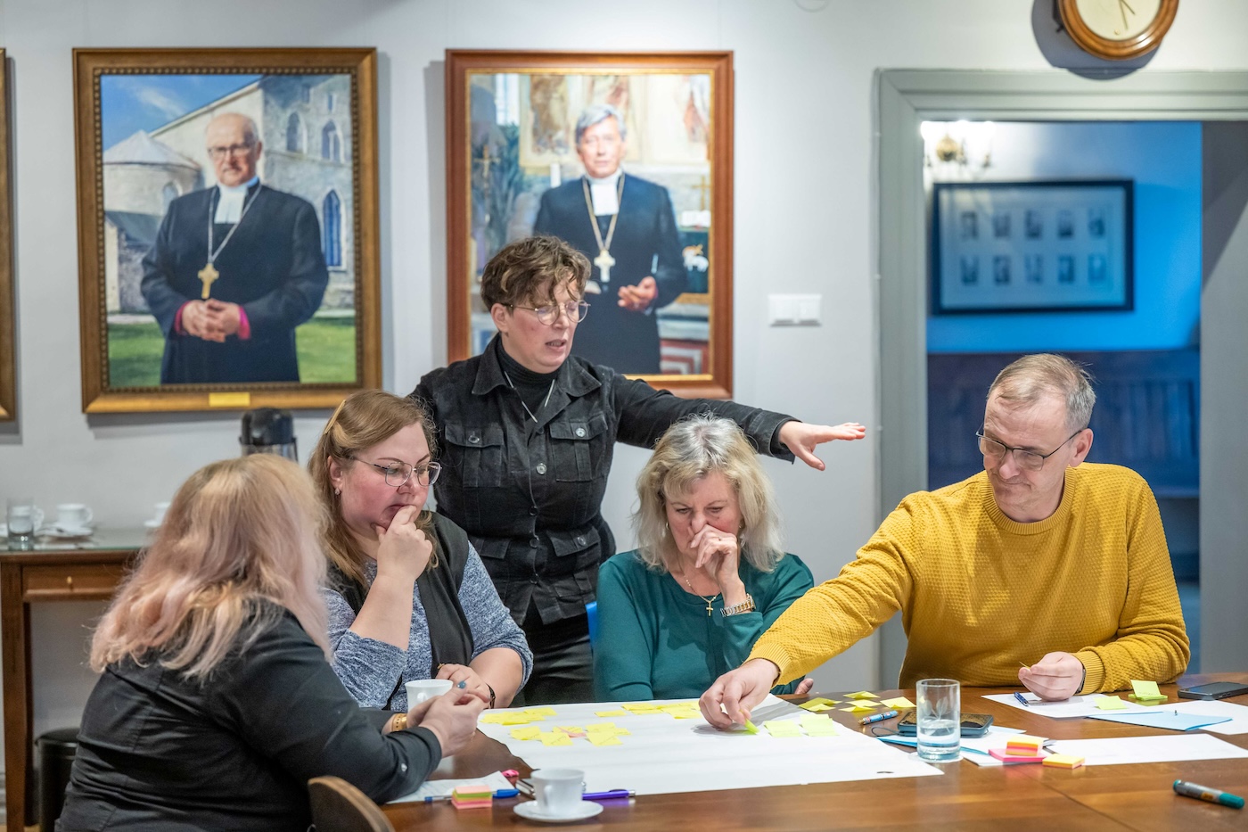 Bildet viser en dame som forklarer noen deltakere rundt et bord hva de skal gjøre