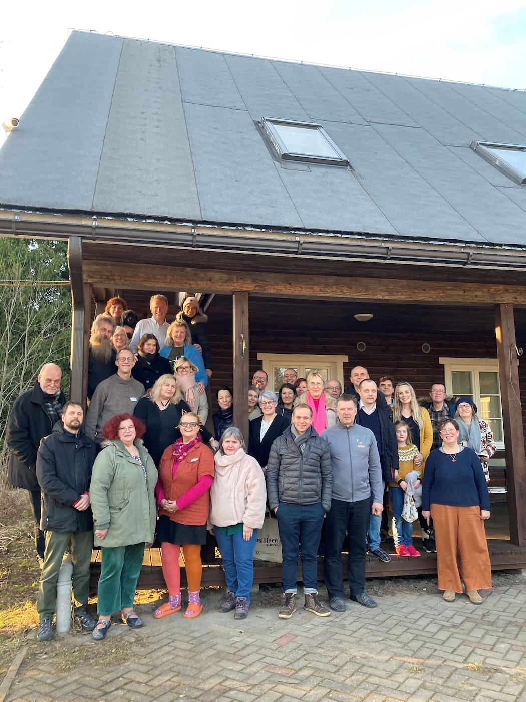 Bildet viser en forsamling som står oppstilt foran et bygg