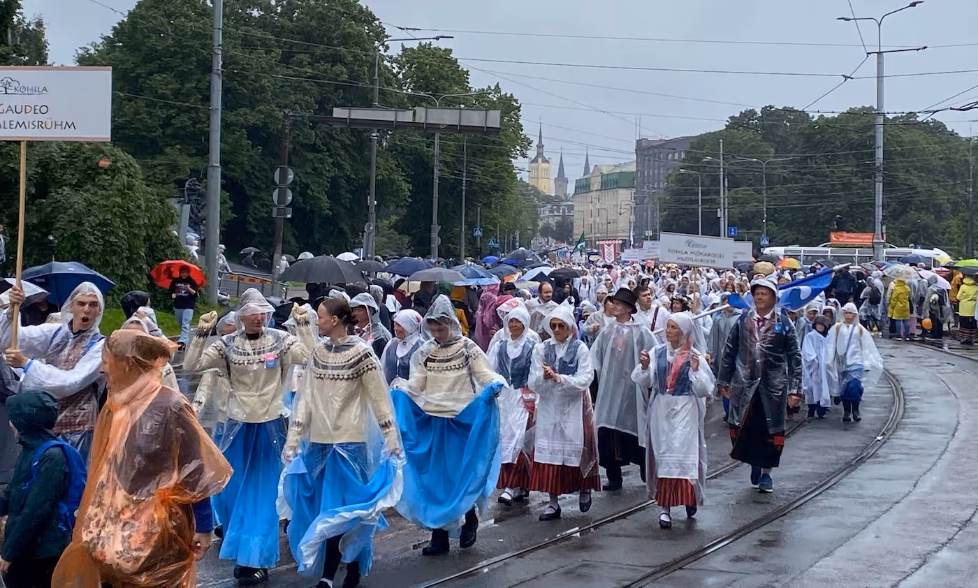 Bildet viser et tog av korister og dansere som går langs veien
