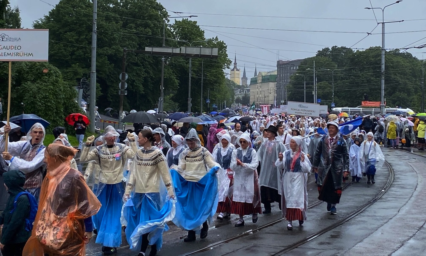 Bildet viser et tog av korister og dansere som går langs veien