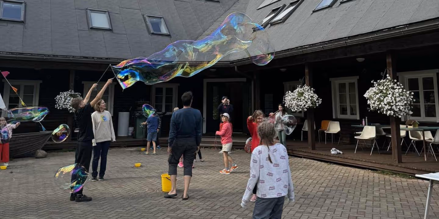 Bildet viser barn og unge som koser seg med å lage store såpebobler