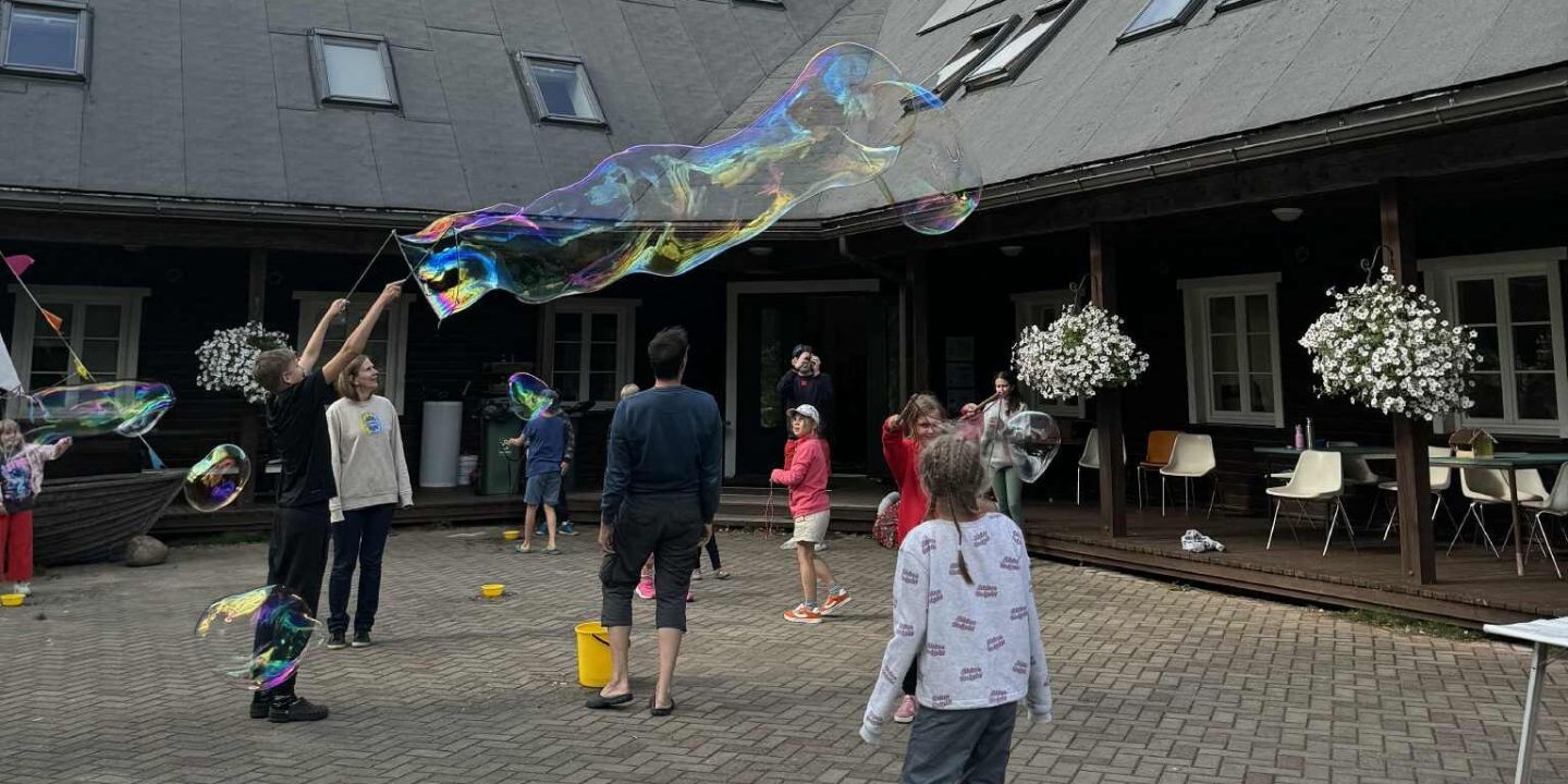 Bildet viser barn og unge som koser seg med å lage store såpebobler