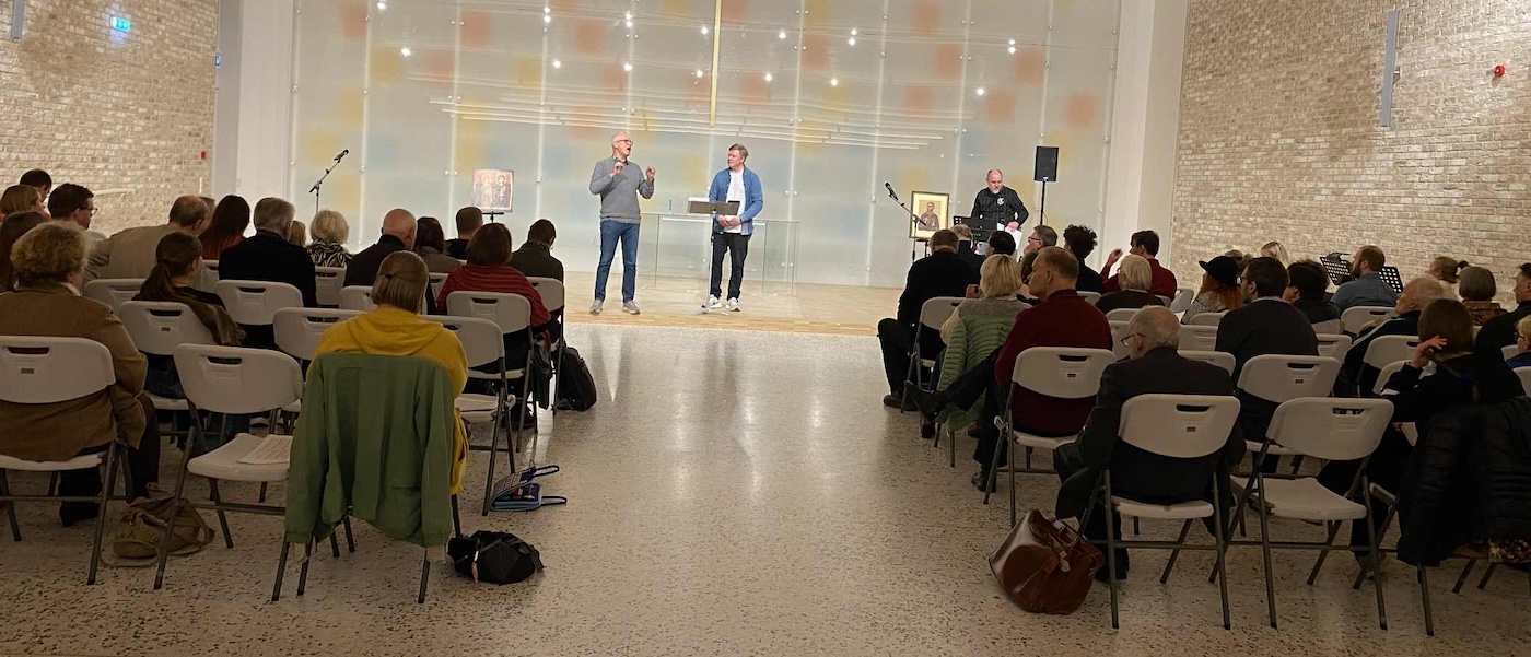 Bildet viser to personer foran en forsamling som underviser om Jesu lignelser