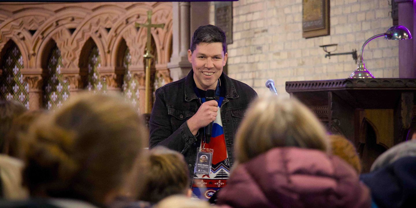 Bildet viser Steve Weston med mikrofon i et kirkerom