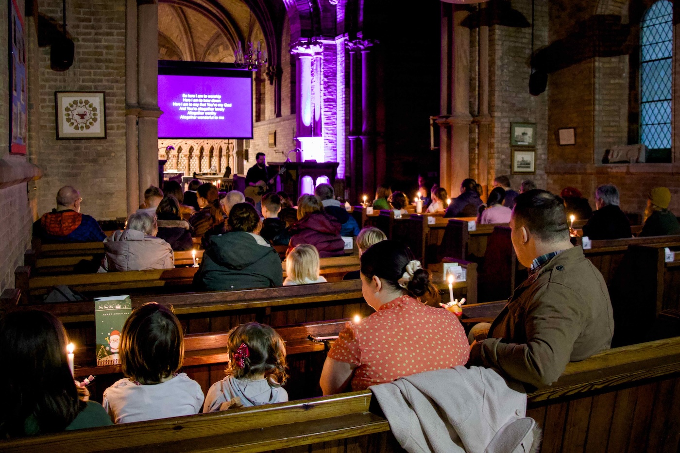 Bildet viser tilhørere sittende på kirkebenker i en kirke