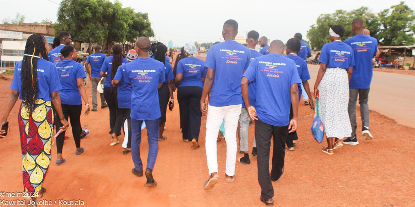 Bildet viser en gjeng med unge voksne mennesker, fotografert bakfra, iført blåe t-skjorter