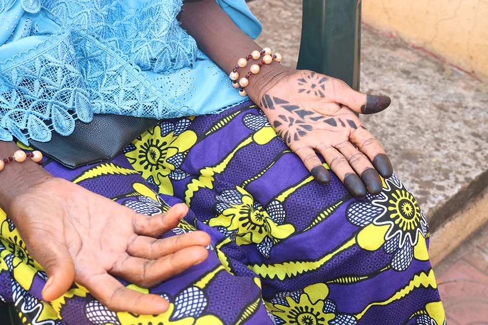 Bildet viser et utsnitt av to hender som er strykket ut på et fang. Den ene hånda er tattovert.