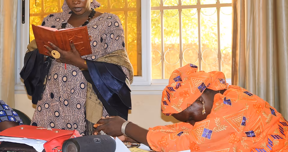 Bildet viser to anonymiserte damer. Den ene tår og leser fra en bok, mens den andre sitter lent forover med hendene foldet