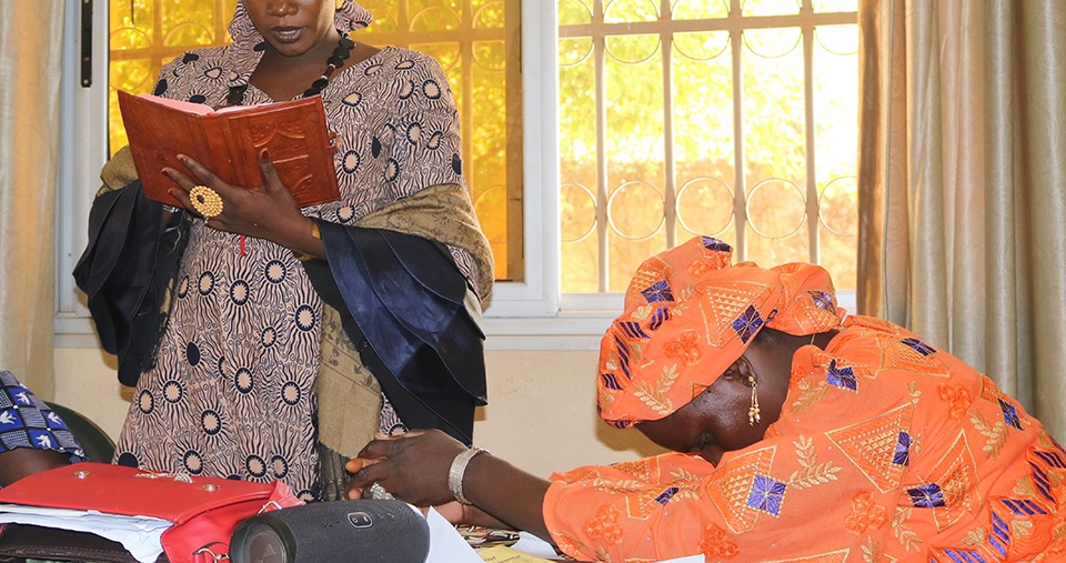 Bildet viser to anonymiserte damer. Den ene tår og leser fra en bok, mens den andre sitter lent forover med hendene foldet