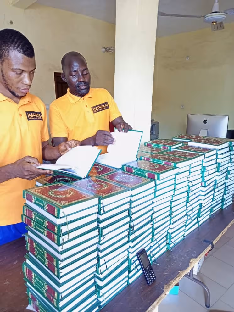 Bildet viser to personer som blar i hvert sitt eksemplar av mosebøkene oversatt til fulani