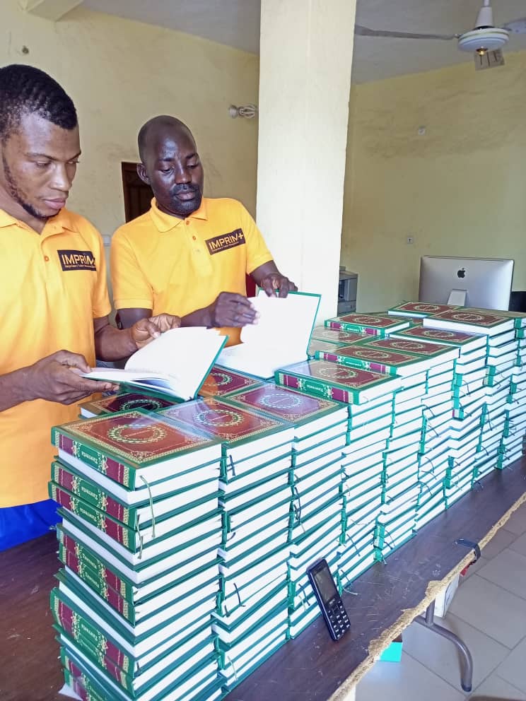 Bildet viser to personer som blar i hvert sitt eksemplar av mosebøkene oversatt til fulani