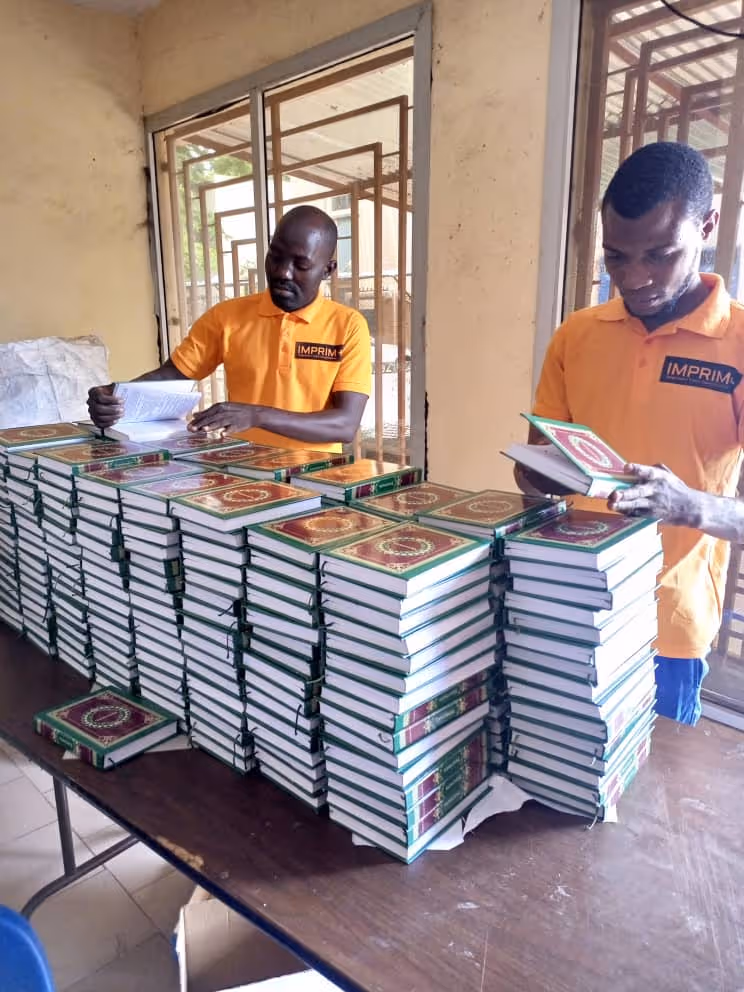 Bildet viser to personer som blar i hvert sitt eksemplar av mosebøkene oversatt til fulani