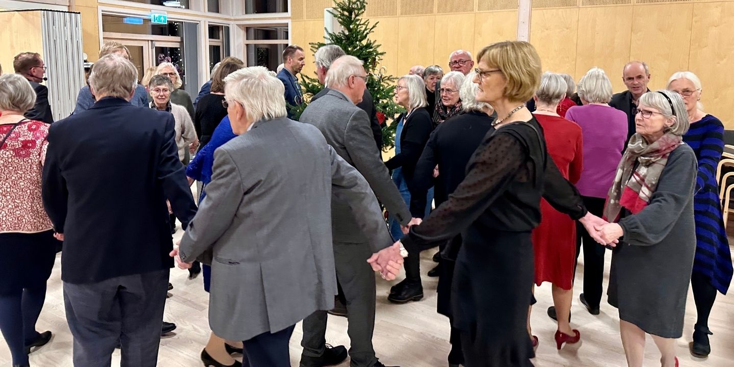 Bildet viser folk som går rundt juletreet