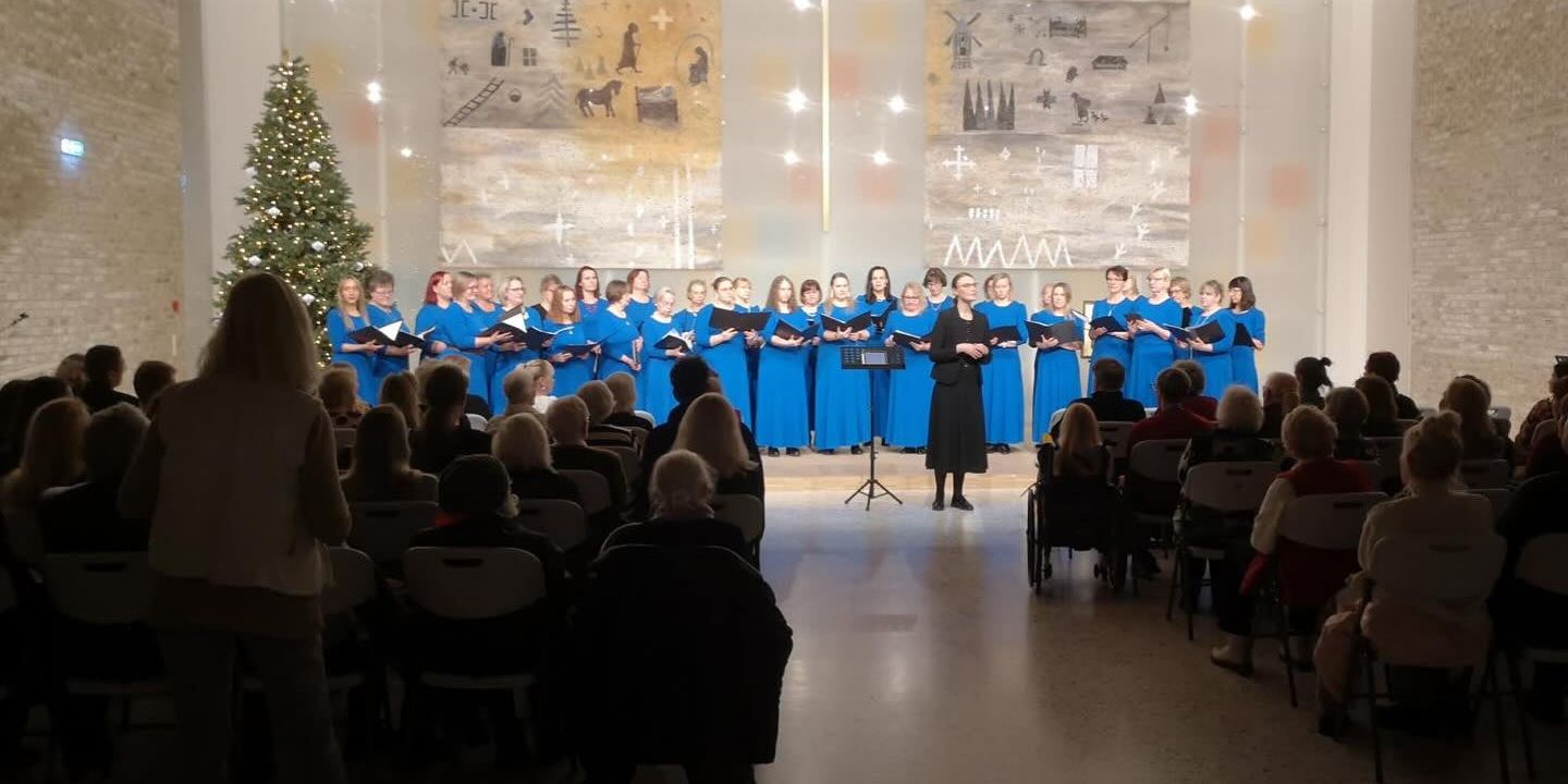 Bildet viser et kor som står framme i et kirkerom og synger