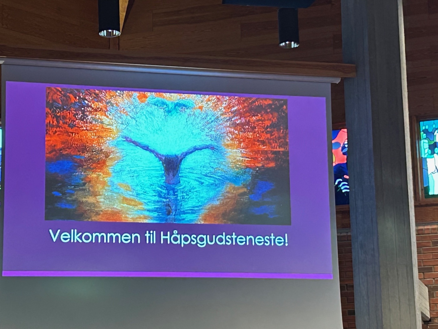Bildet viser teksten "velkommen til håpsgudstjeneste" på et lerret
