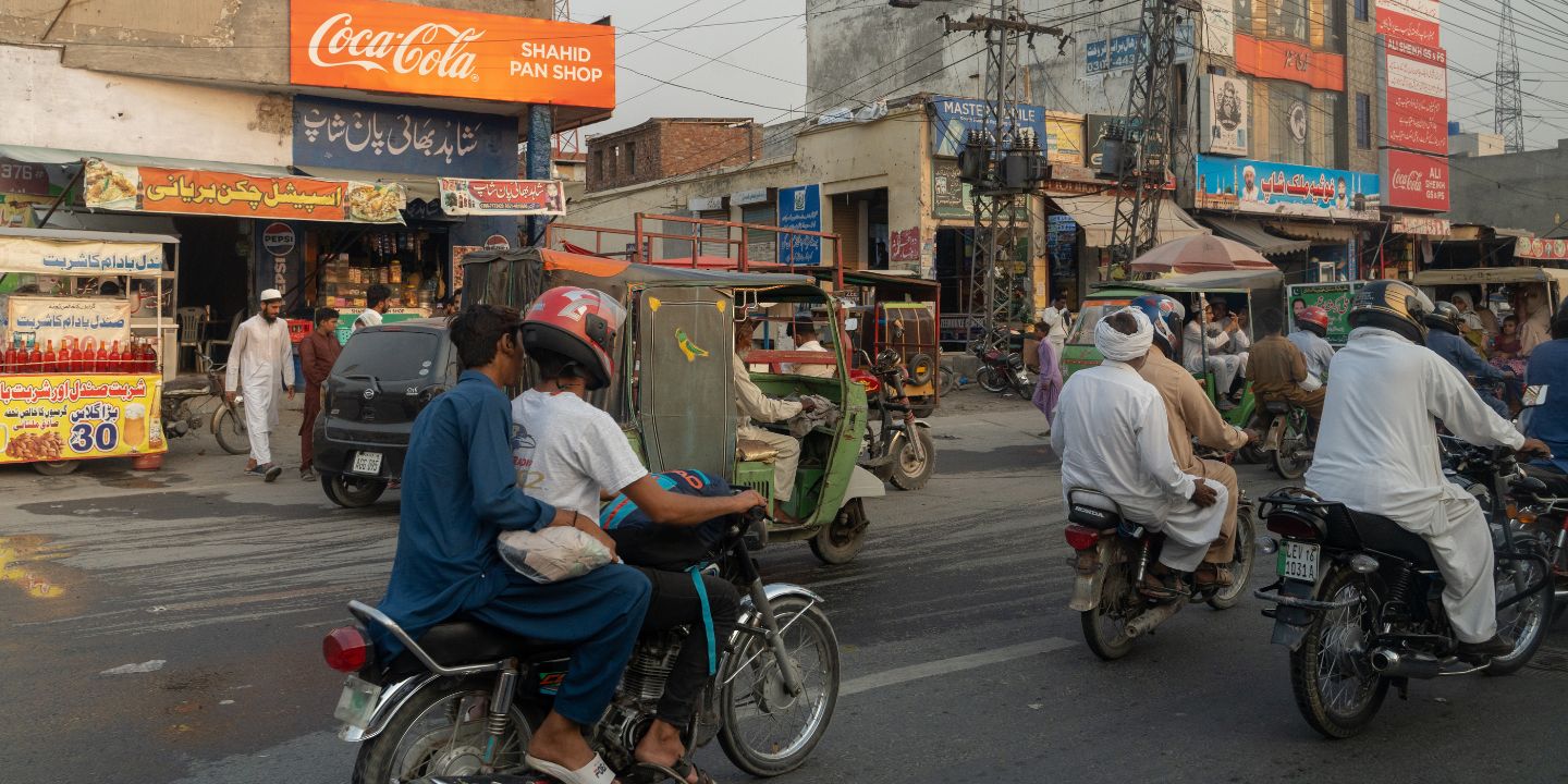Bildet viser personer på mopeder i en trafikkert gate i Pakistan