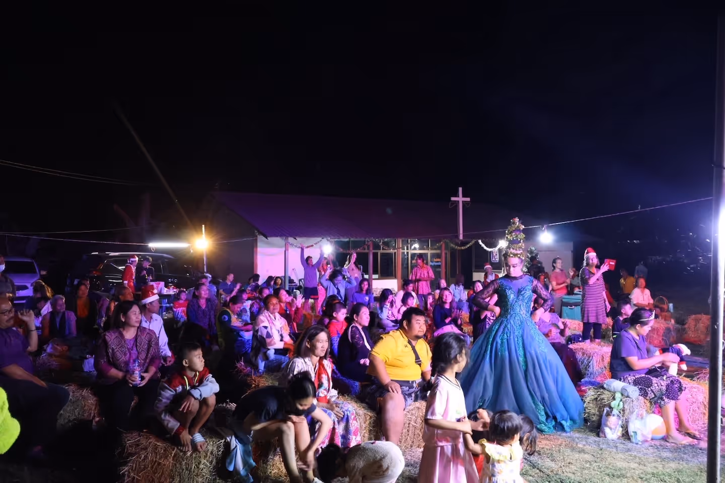 Bildet viser en forsamling som sitter foran en scene utendørs