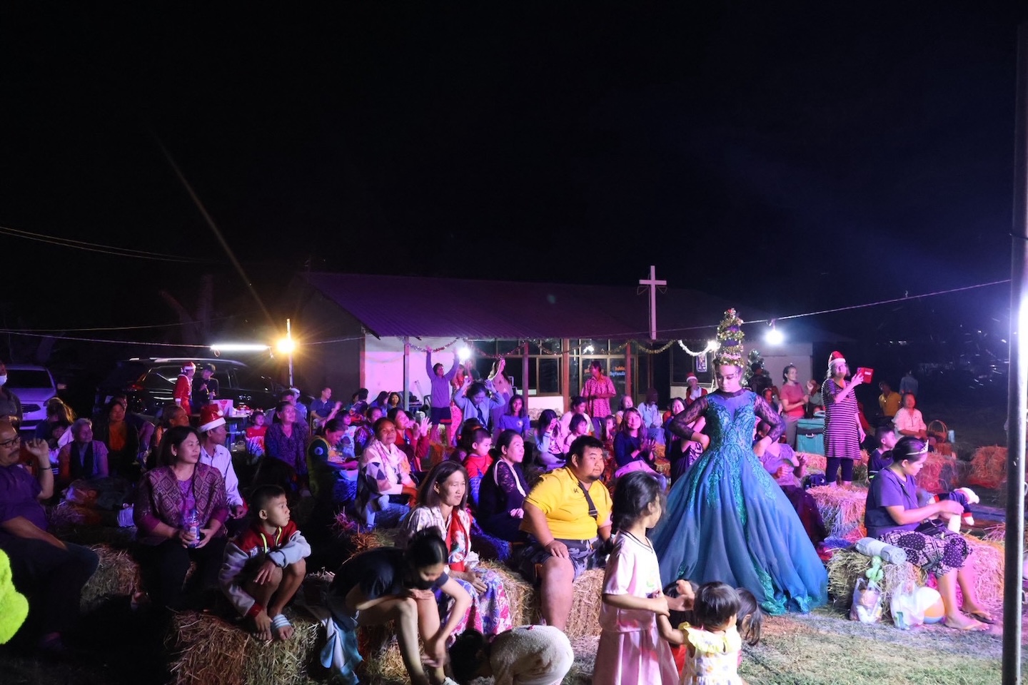 Bildet viser en forsamling som sitter foran en scene utendørs