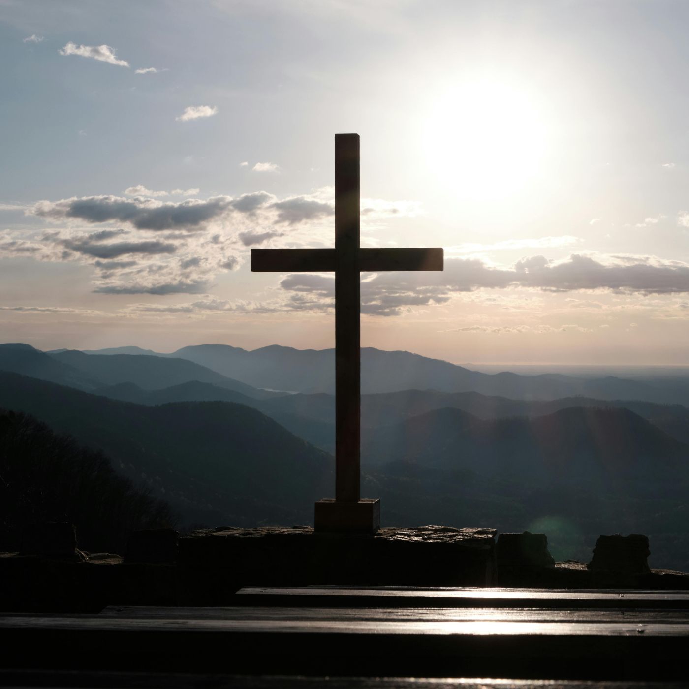 Bildet viser et kors med sollys i bakgrunnen