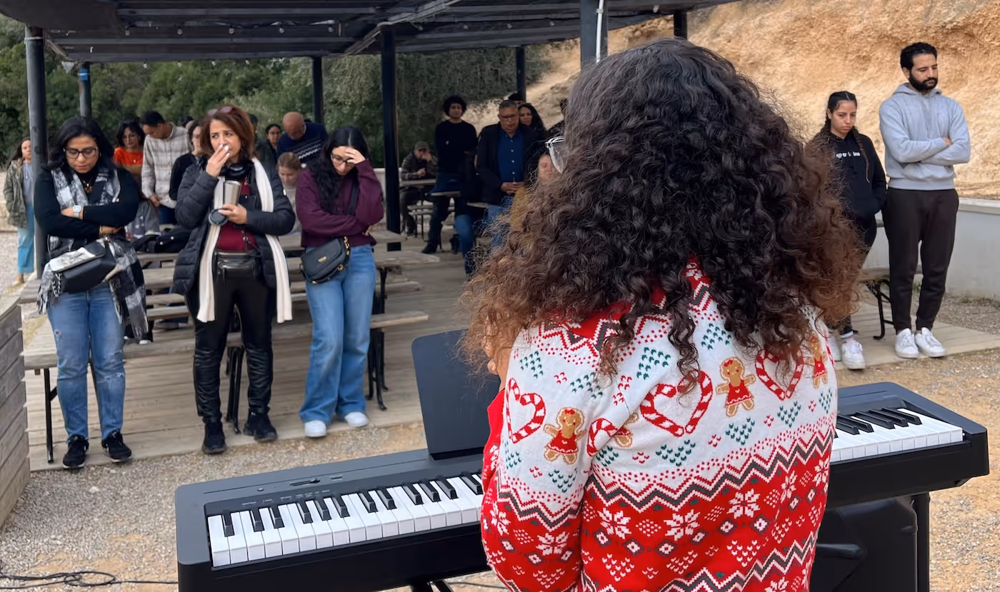 Bildet viser bakhodet til ei dame som spiller op et keyboard utendørs. En håndfull mennesker står foran keyboardet