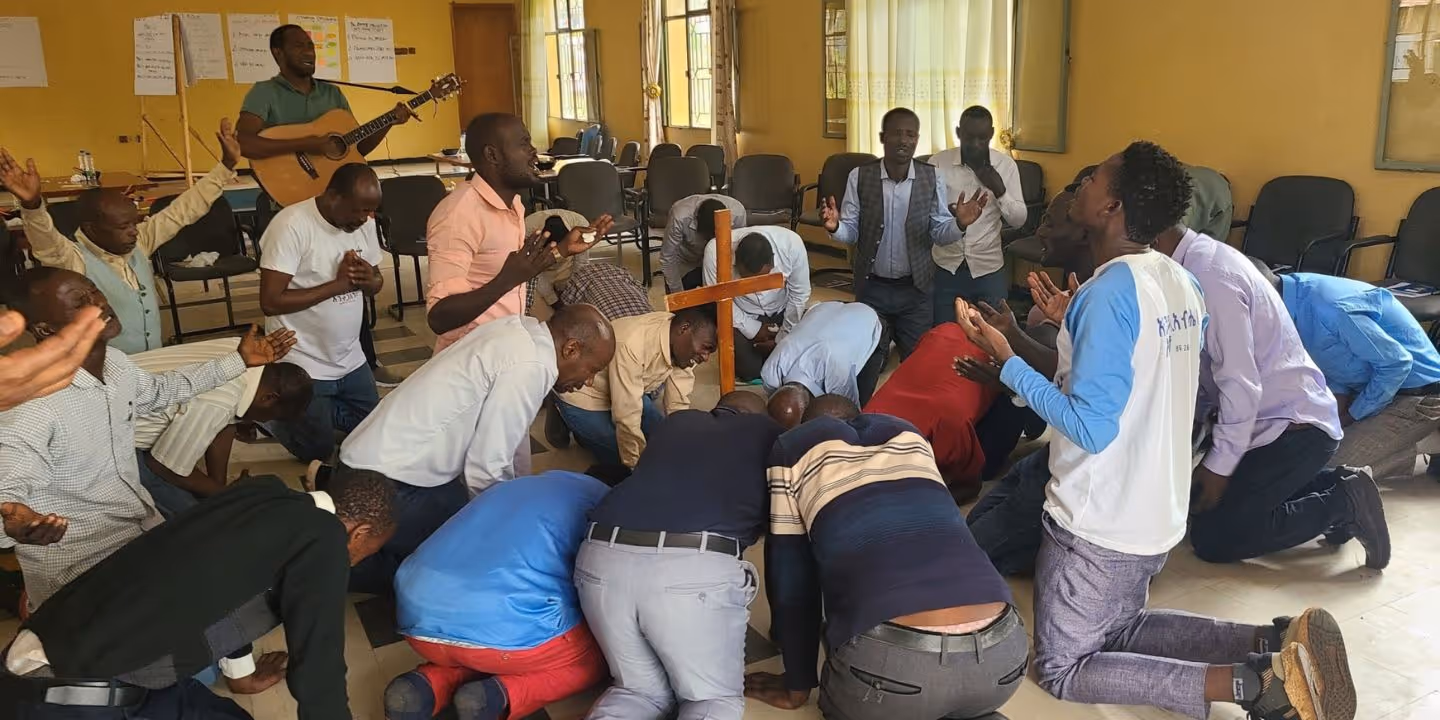 Bildet viser en gruppe mennesker sammen i ring under bønn