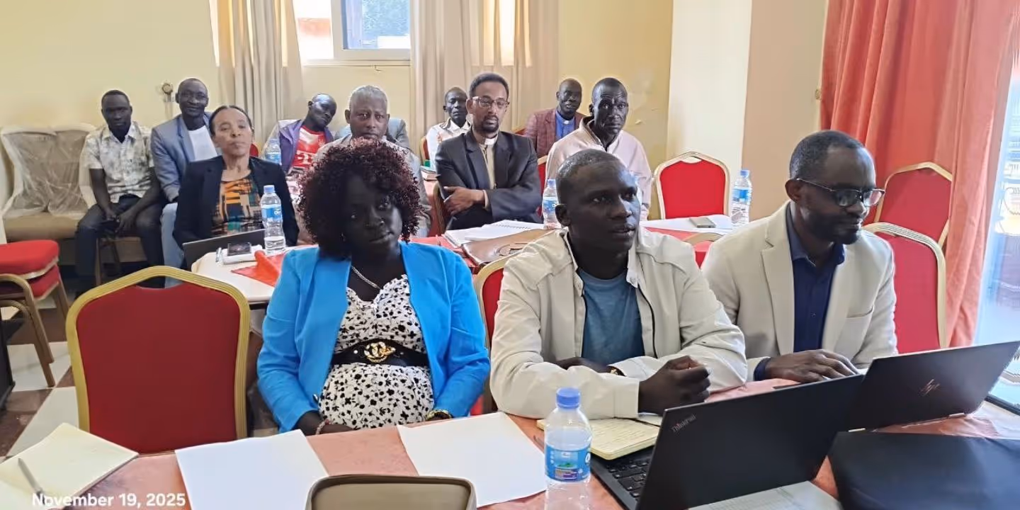 Bildet viser en forsamling mennesker som sitter ved pulter og fulger med på noe som foregår foran dem