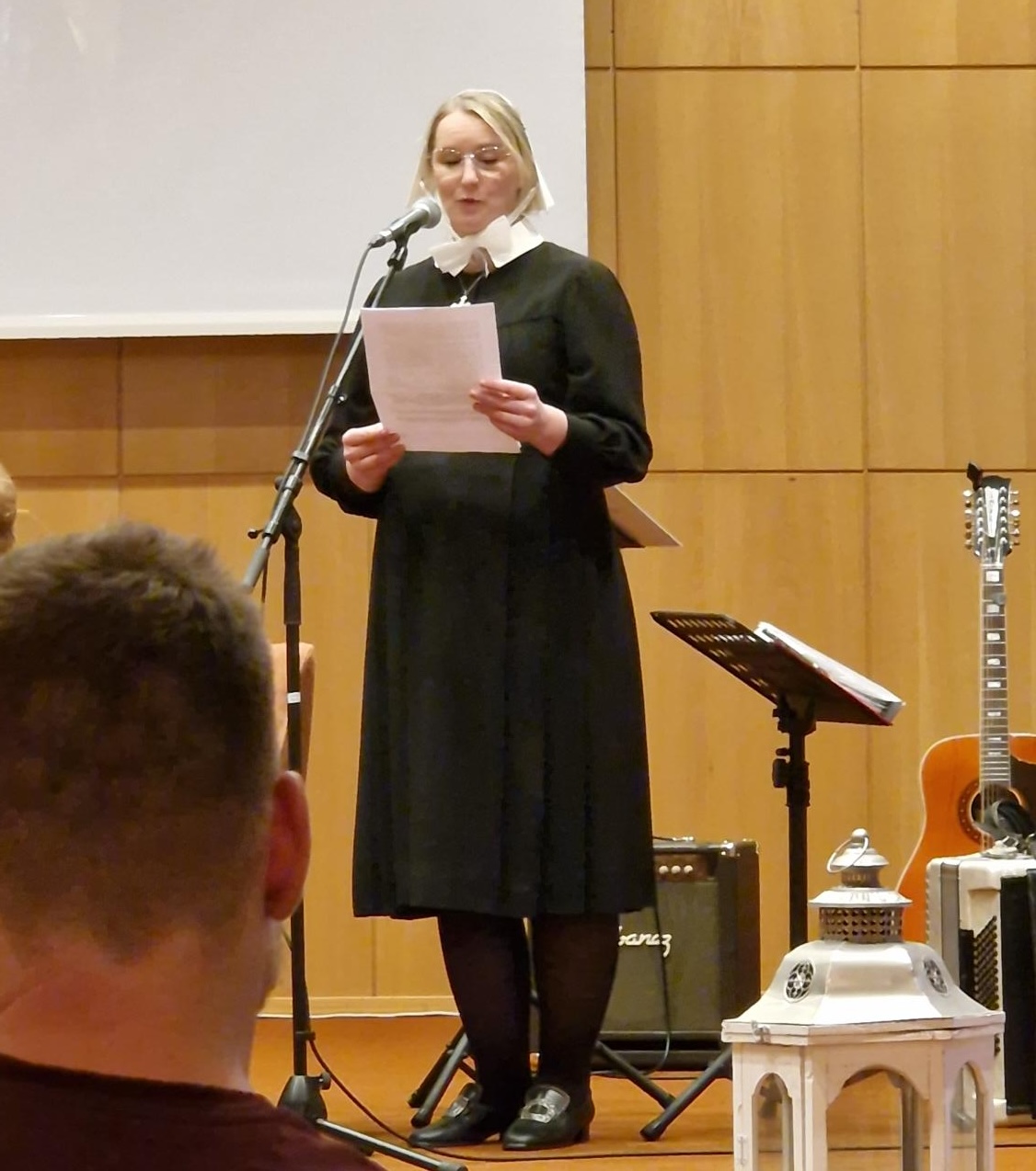 Bildet viser Kristine Hurlen i diakonissedrakt som leser opp en andakt av Sina Løken