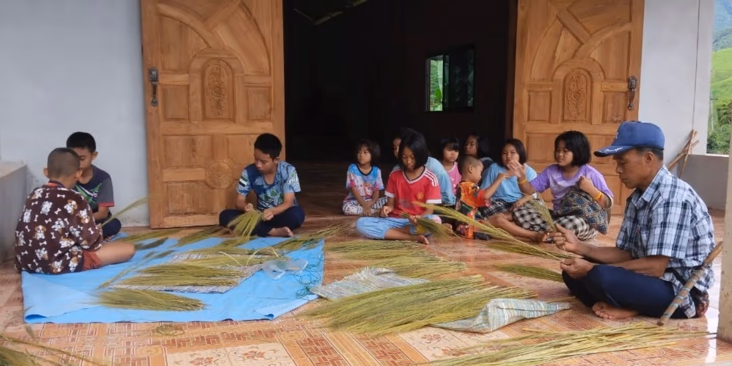 Bildet viser barn som lager feiekoster på lørdagsklubben i NaPong, nord i Thailand.