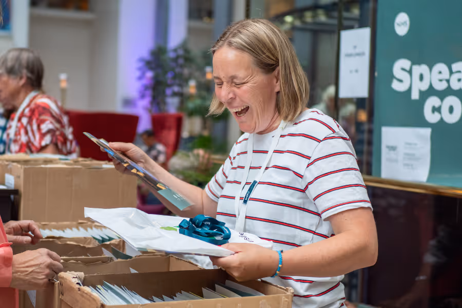 Bildet viser et nærbilde av ei dame som forbereder mapper ved registrerings-standen