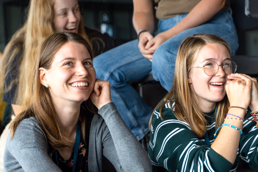 Bildet viser to personer som smilende følger med på noe som skjer foran dem