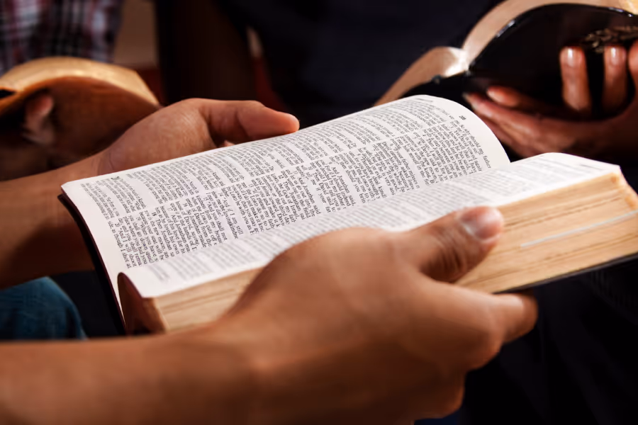 Bildet viser to hender som blar i en bibel