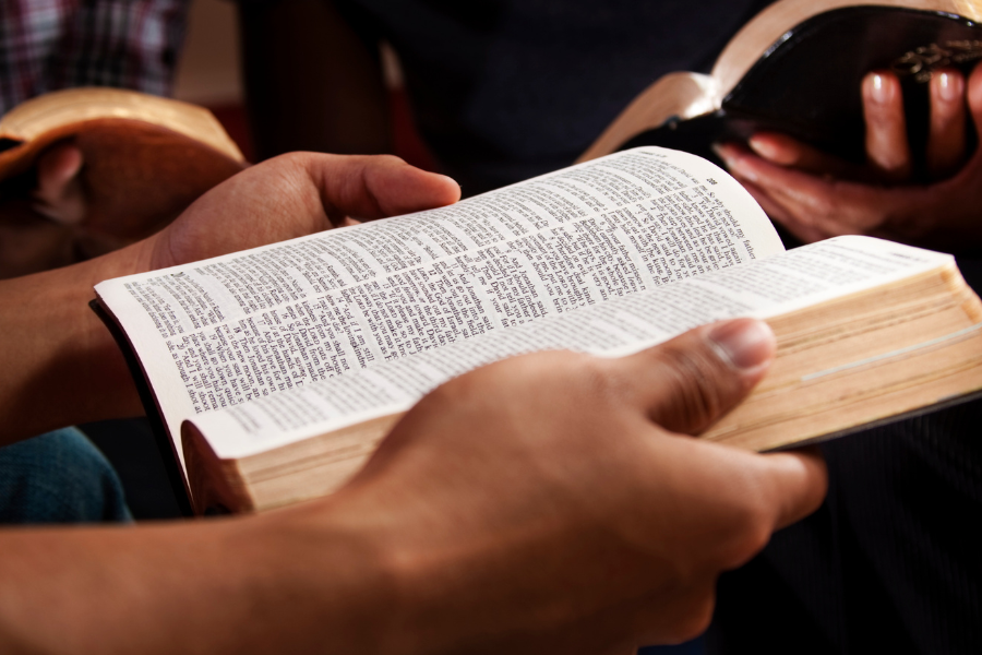 Bildet viser to hender som blar i en bibel