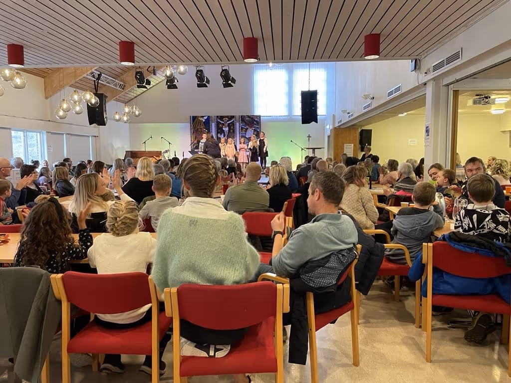 Bildet viser en forsamling som ser noen barn som opptrer på en scene