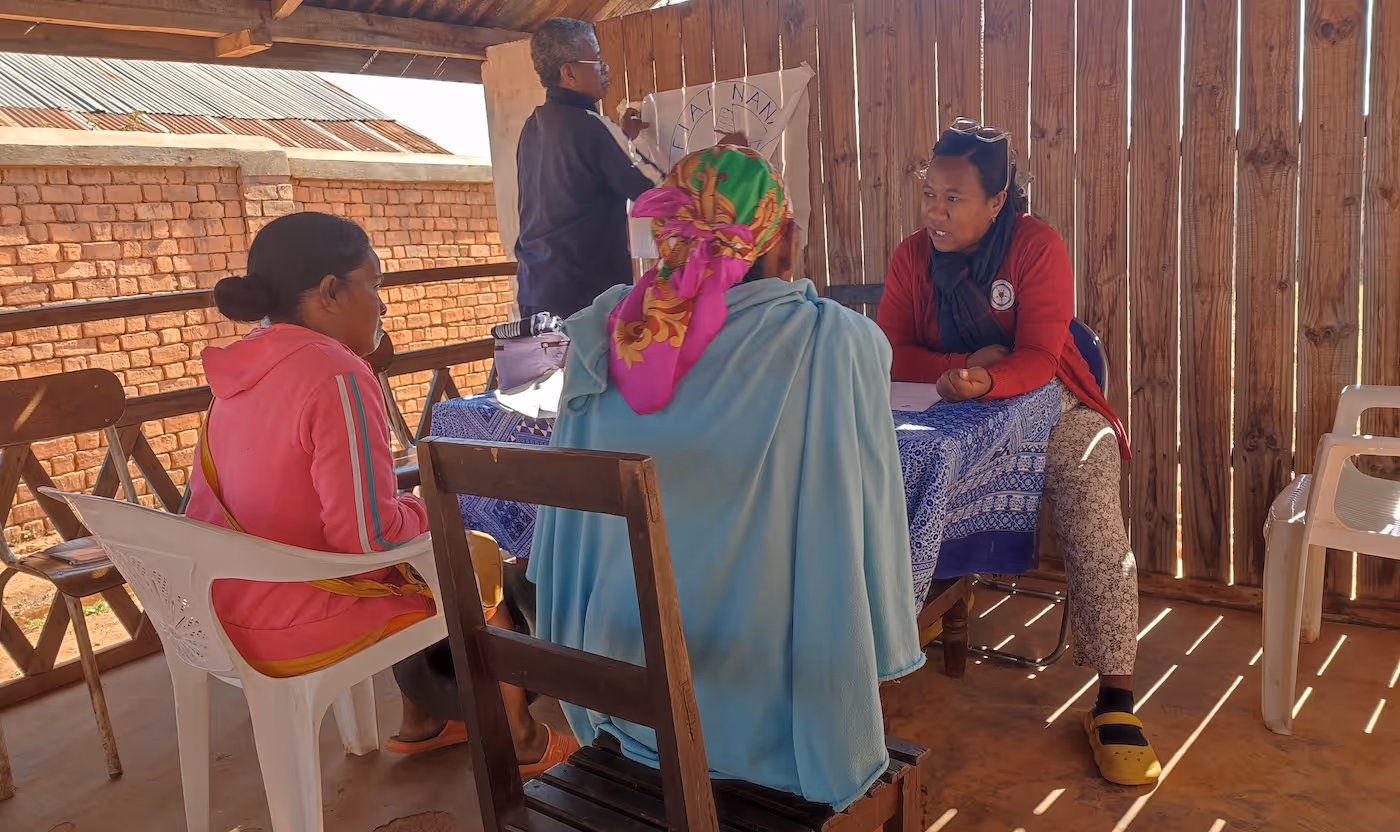 Bildet viser fire personer som sitter rundt et bord i skyggen