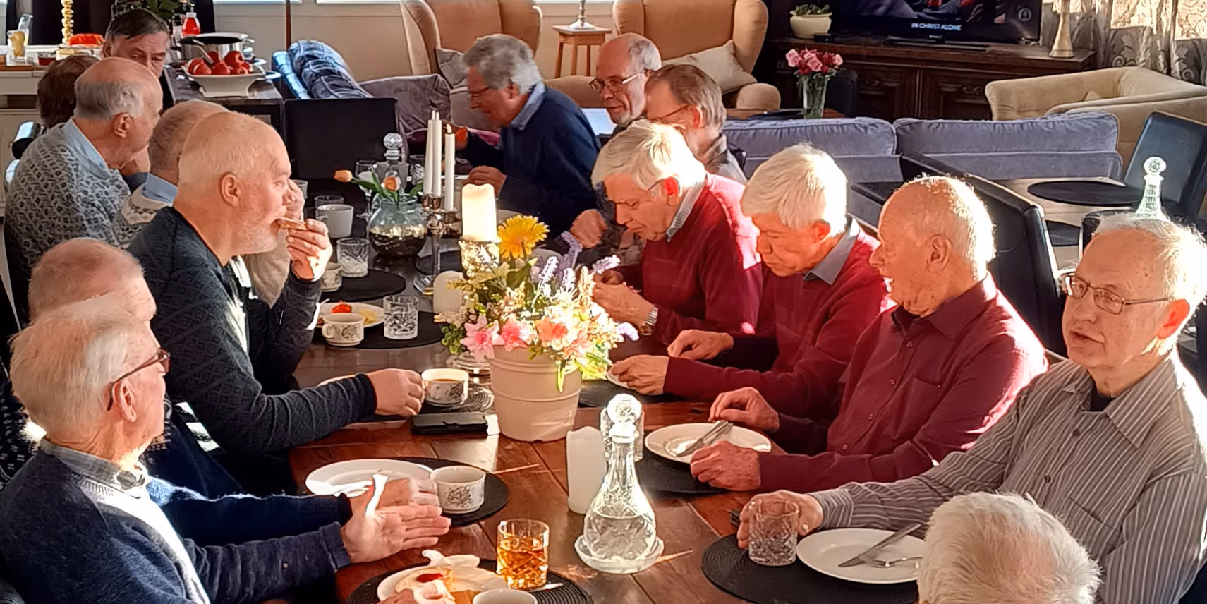 Bildet viser en gruppe personer rundt et matbord som spiser sammen