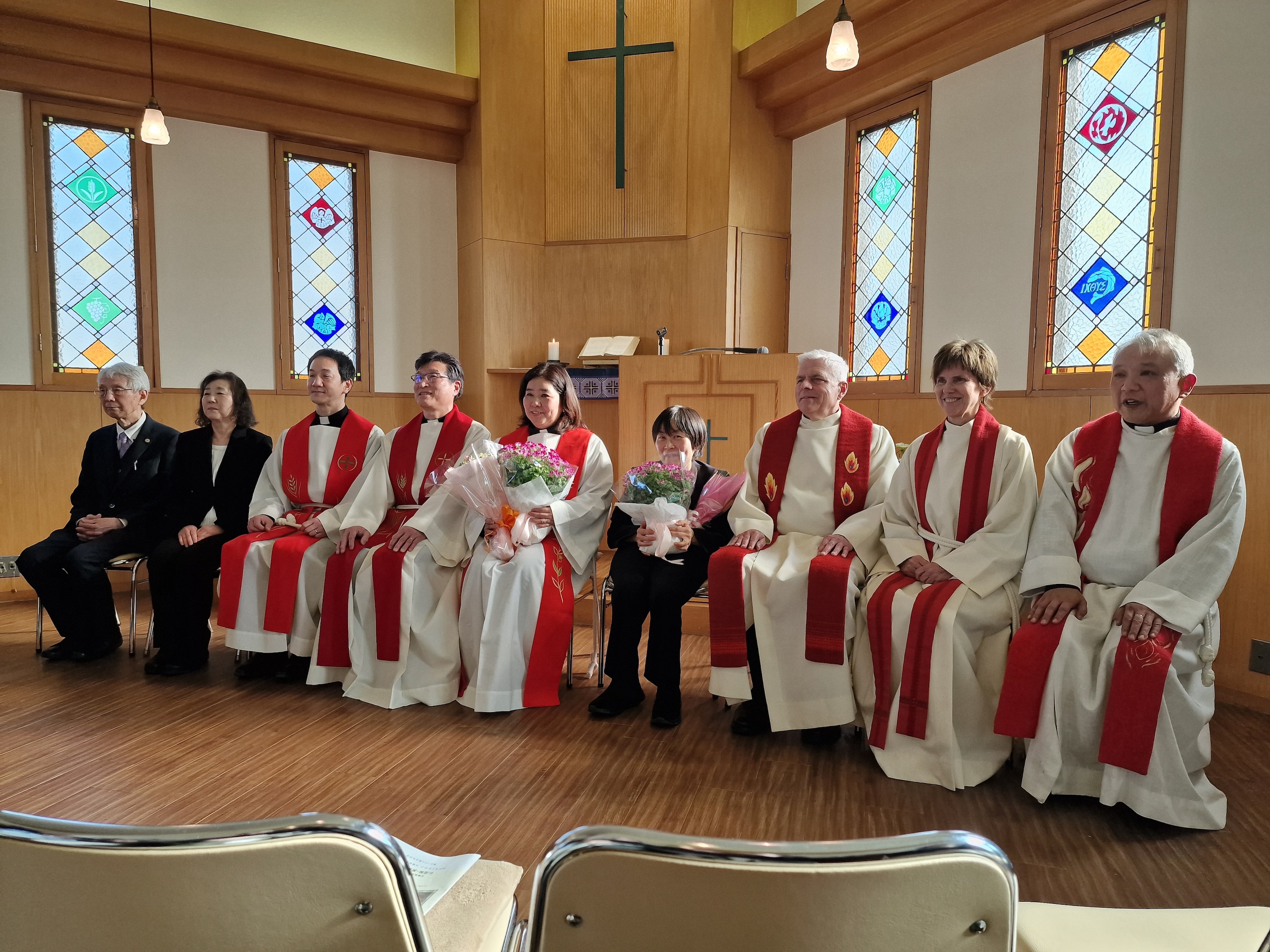 Bildet viser en gruppe på ni personer, deriblant flere prester, sittende på en rekke i et kirkerom