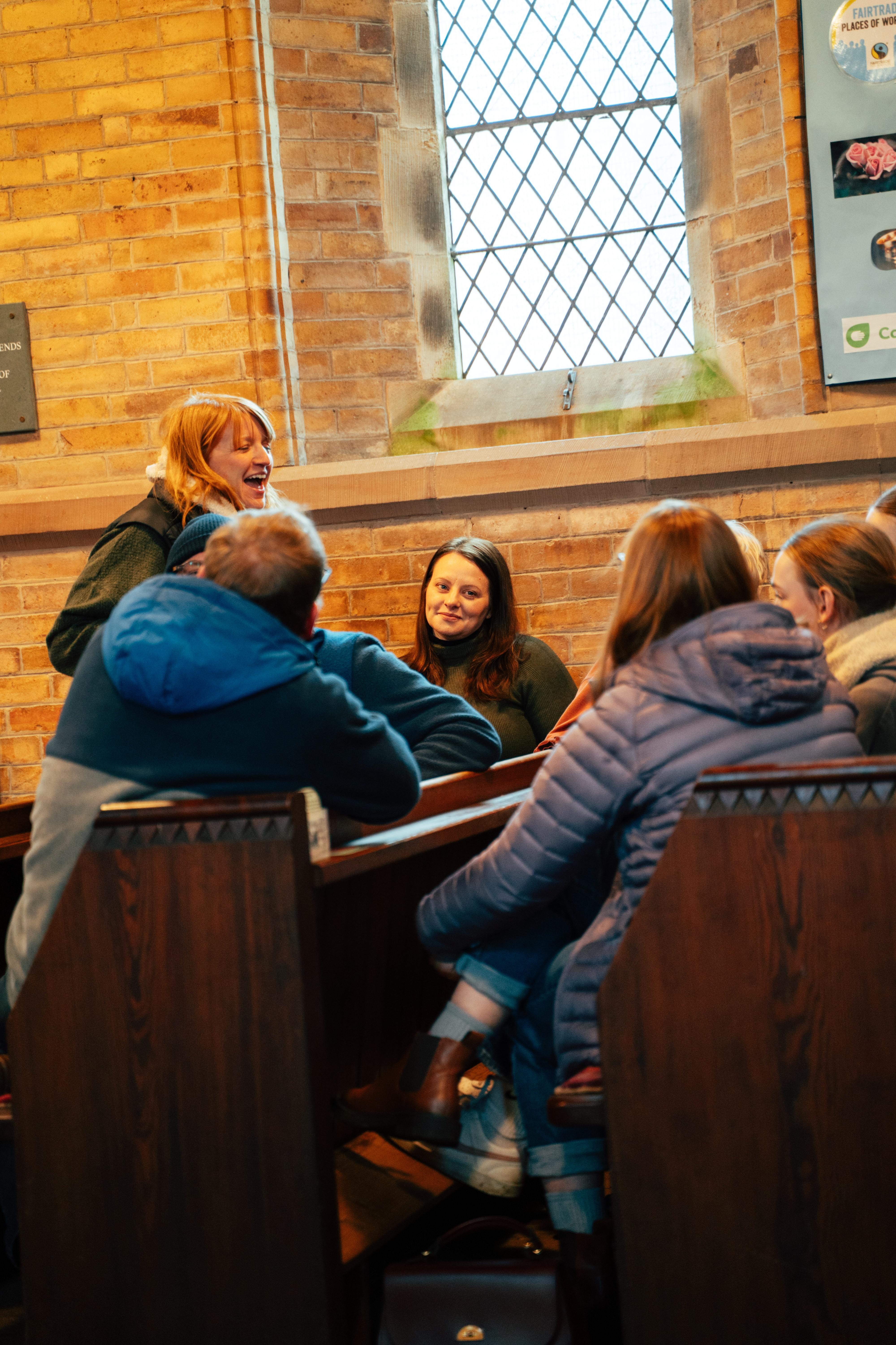 Bildet viser unge mennesker i samtaler i kirkebenken i St. Aidan's