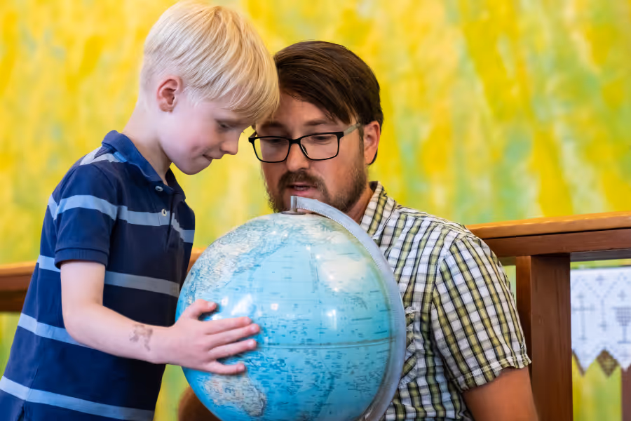 Bildet viser et barn og en mann som ser sammen på en globus