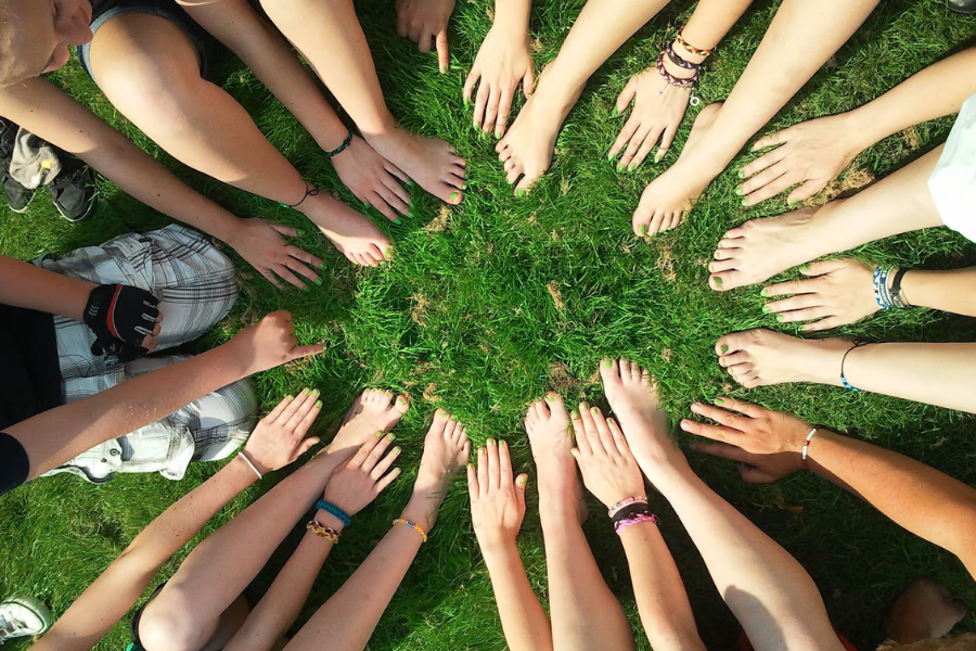 Bildet viser hender og føtter i en ring på gress