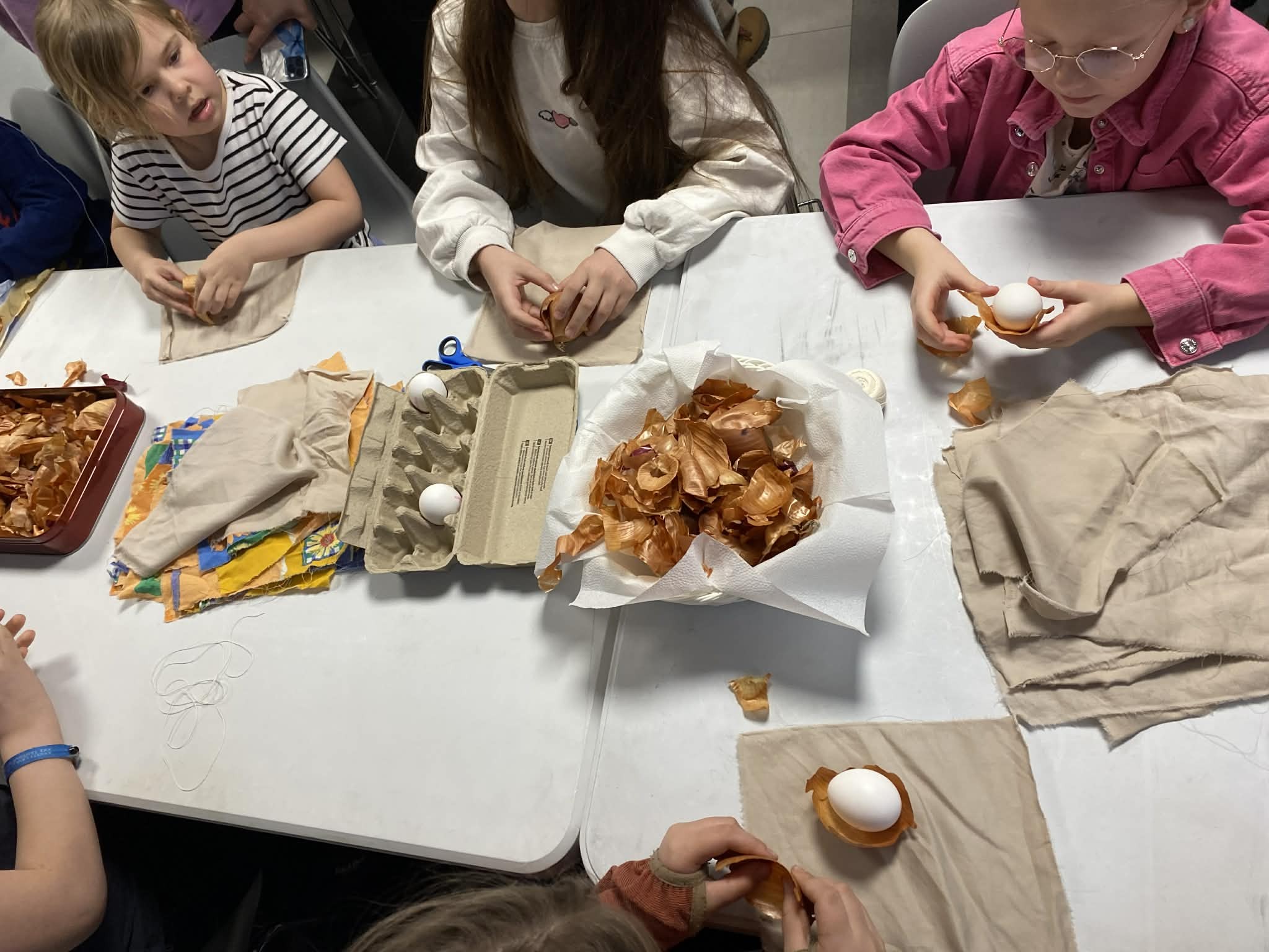 Bildet viser barna i Saku som pakker egg med løkskall