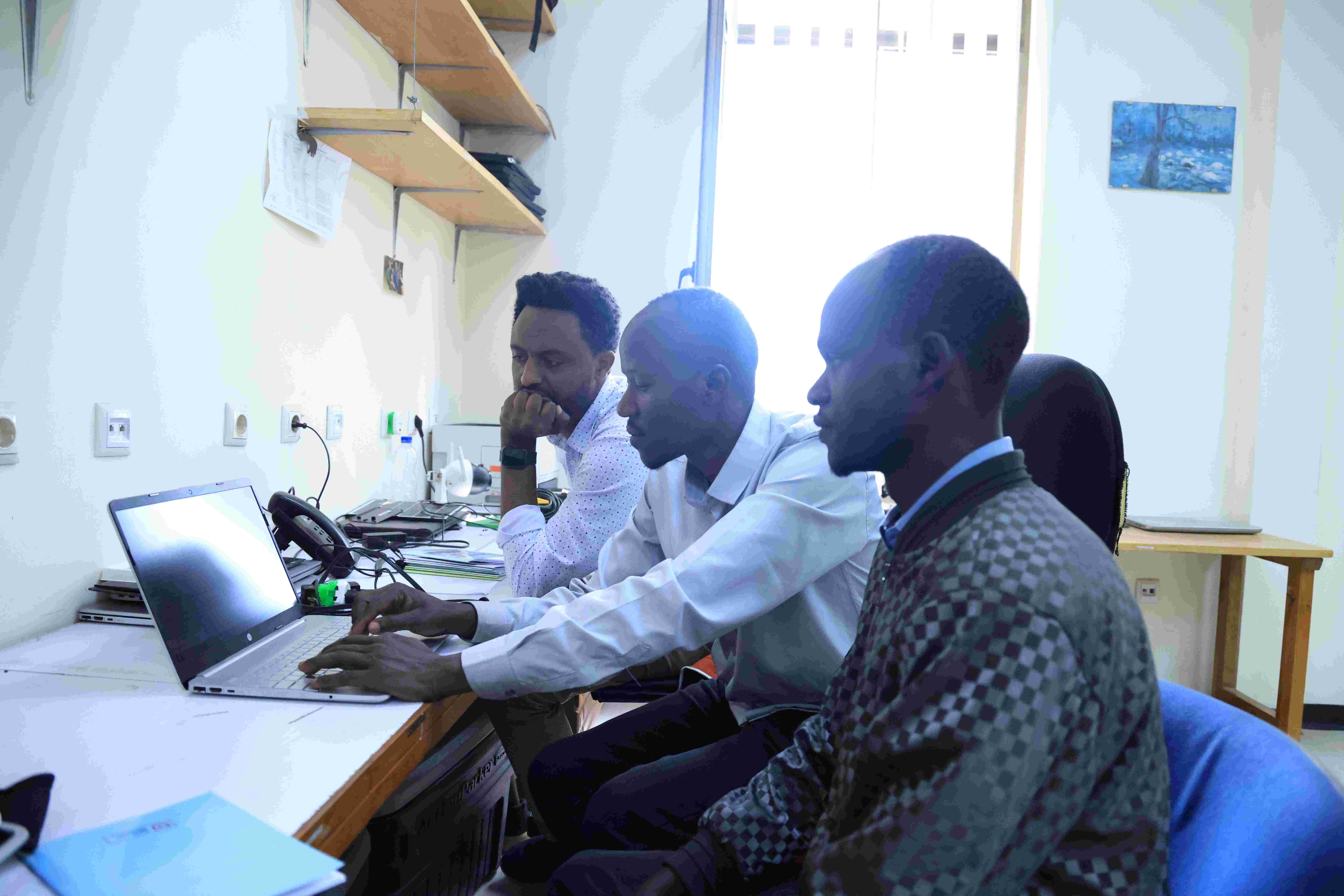 Bildet viser tre personer som jobber sammen foran en datamaskin